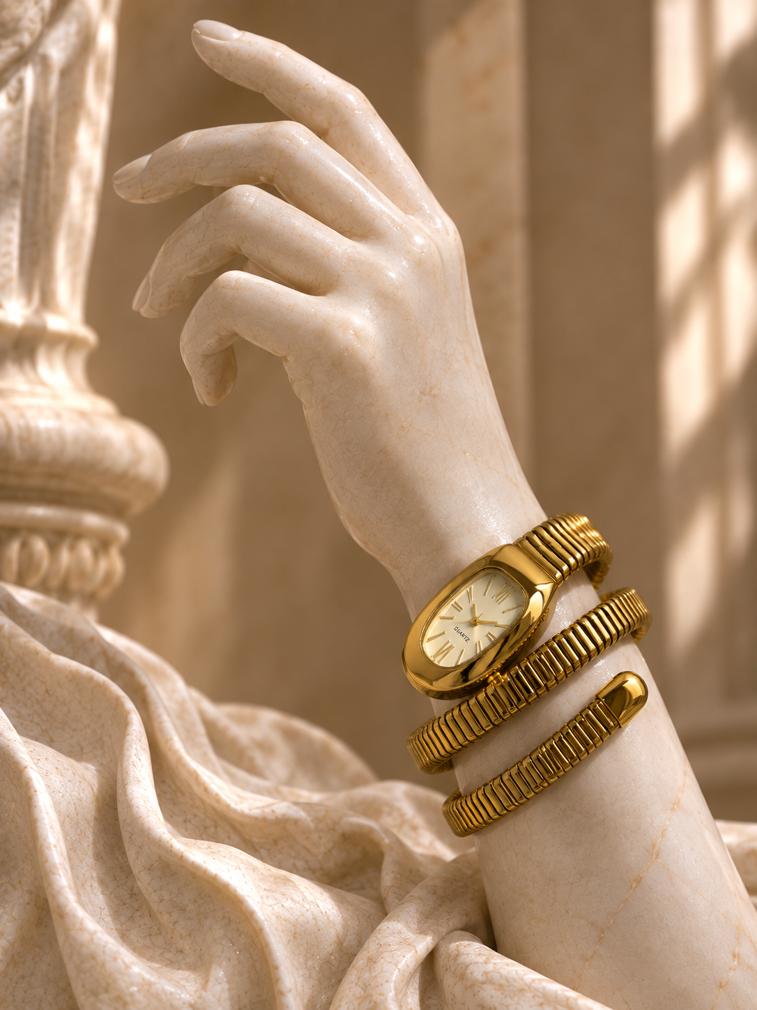 A close-up of a white marble statue arm and hand wearing a gold wristwatch and two stacked gold bangles, set against a warm beige classical architectural background.
