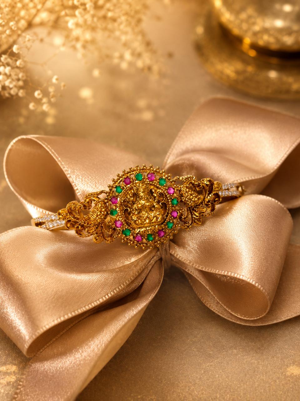 An ornate gold filigree hair claw clip with colorful gemstone accents, displayed on a large champagne-colored satin ribbon bow against a warm, golden background.