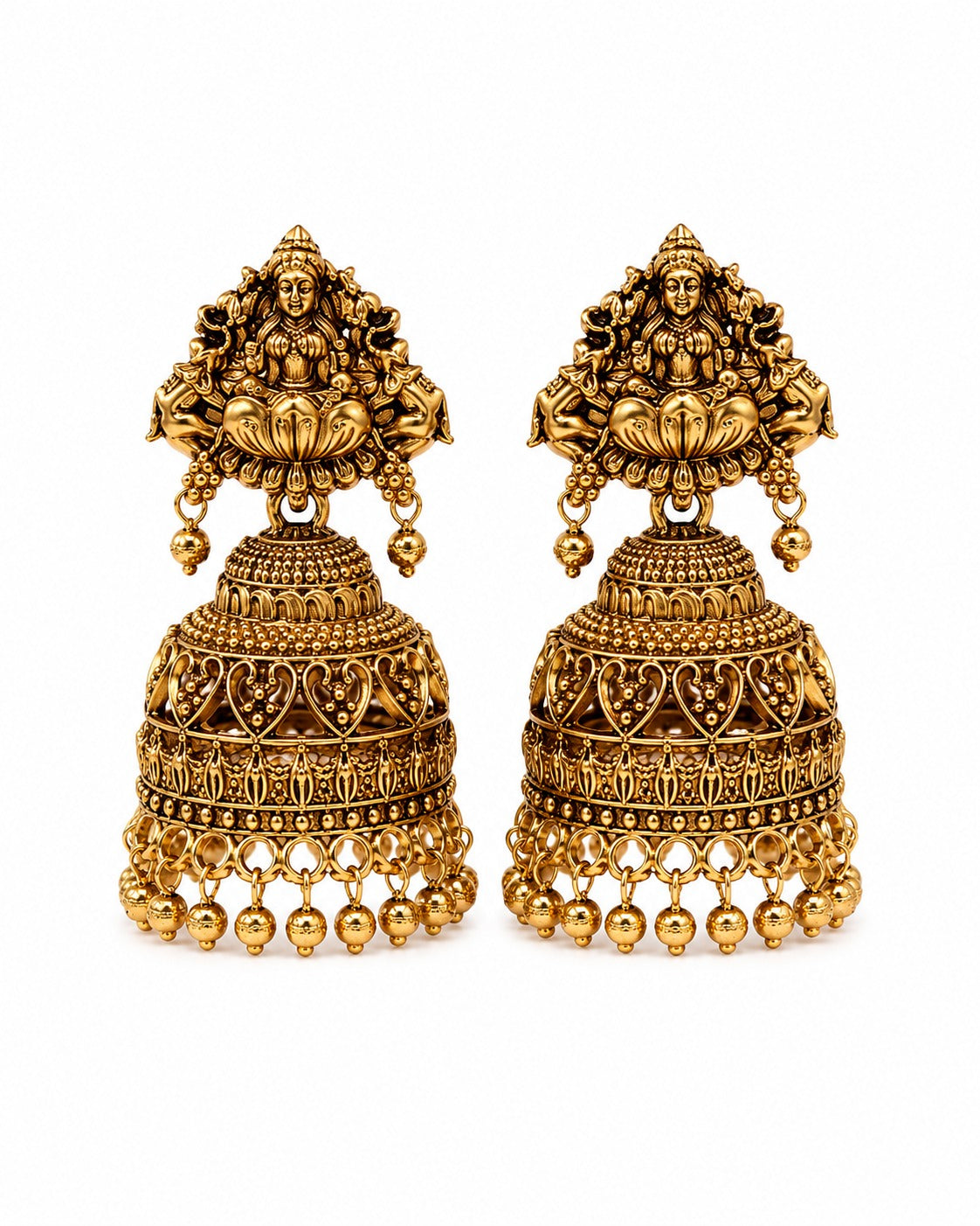 A pair of ornate gold-toned Indian jhumka earrings with detailed filigree, dangling bell-shaped drops, and deity motifs at the top, shown on a plain white background.